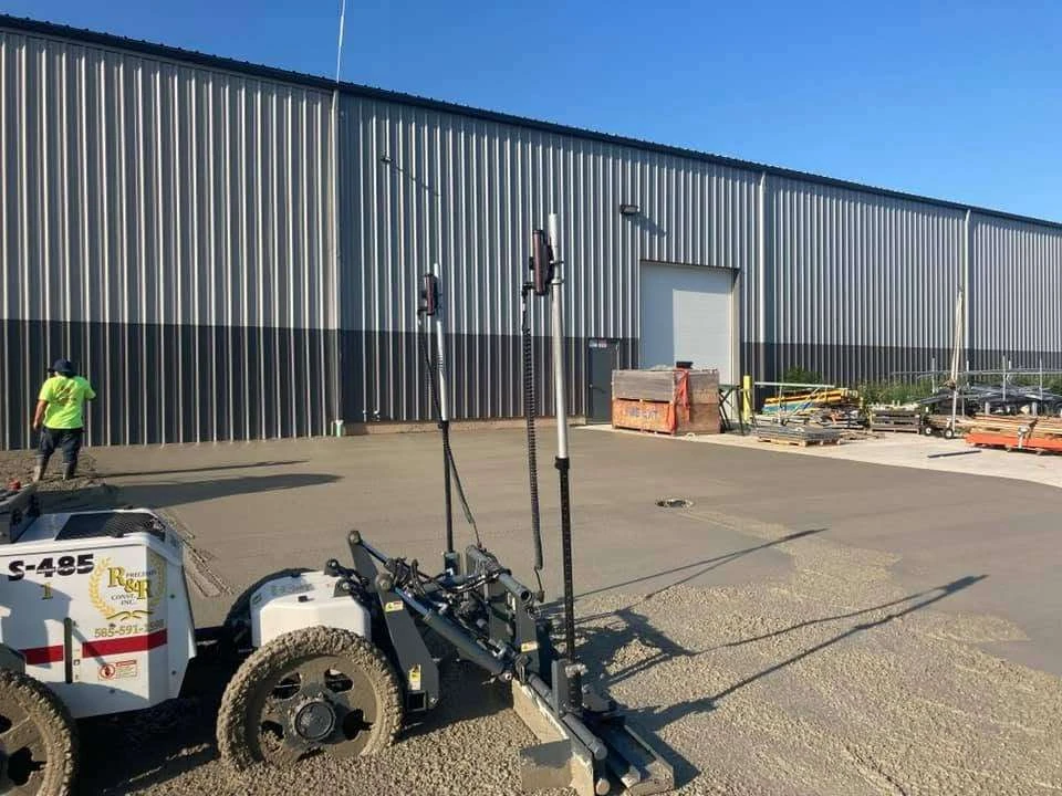 R&R laser screed placing concrete beside a commercial building